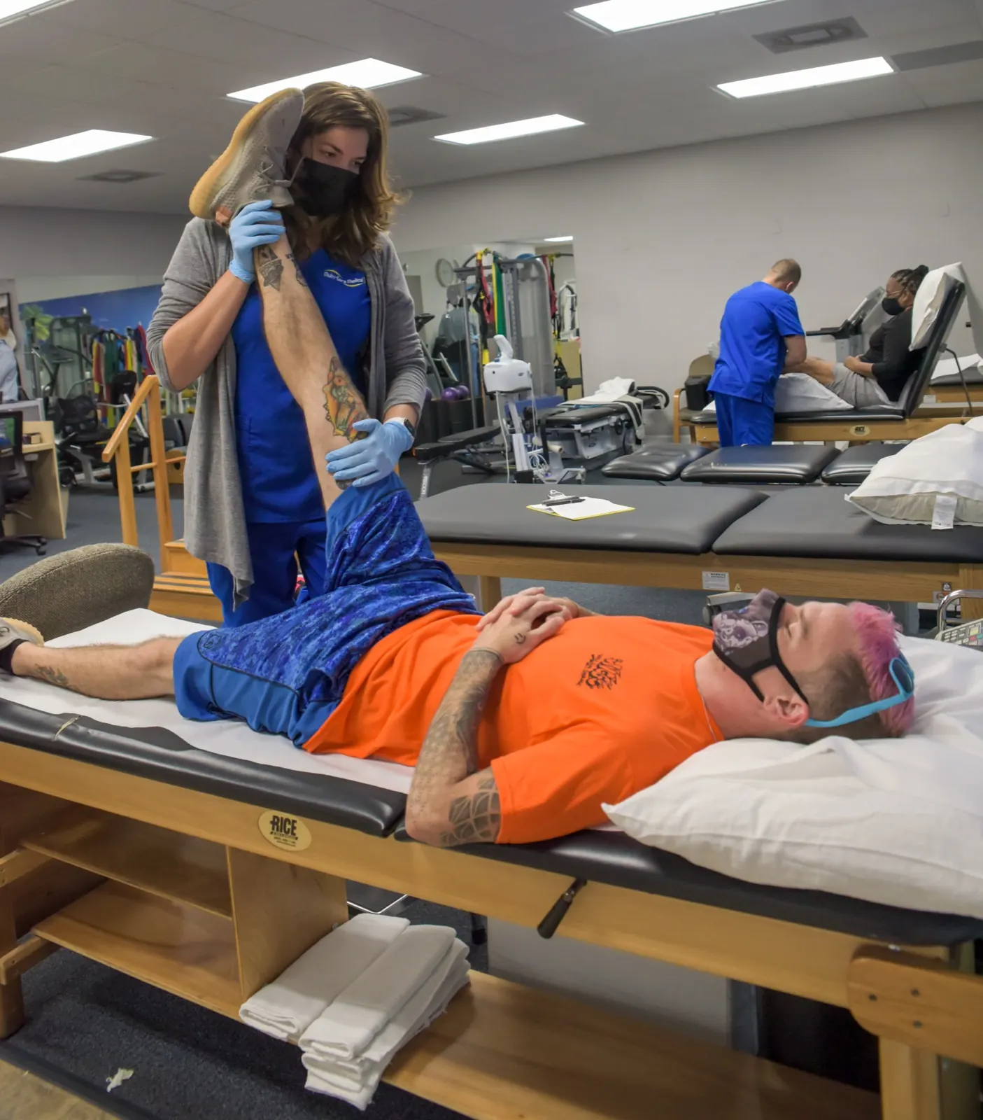 Multi-Care Medical therapist guiding a patient through a leg stretch in the treatment suite